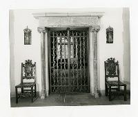 Generated thumbnail: Ornate Iron Gate with Carved Stone Surround and Chairs