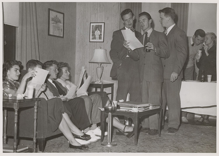 Group reading from printed papers at Kappa Sigma party