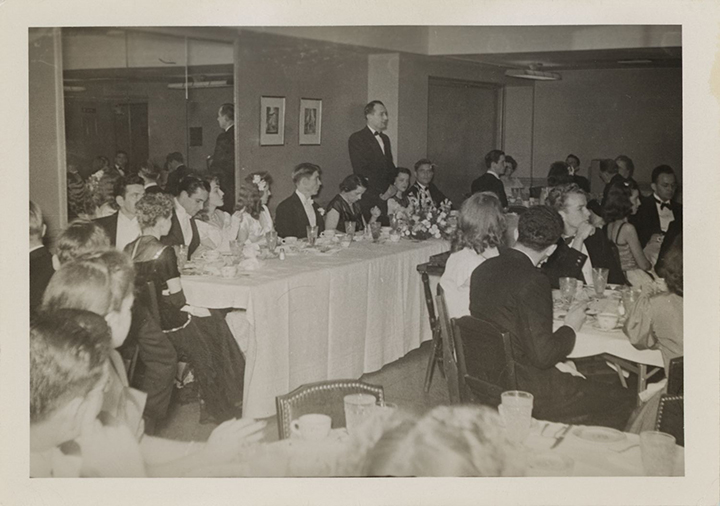 Speaker stands at the head table of formal banquet